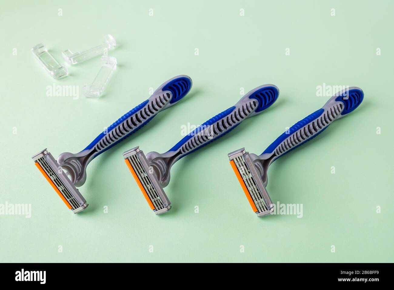 Three new disposable shaving razors with triple blade lie in a row on a