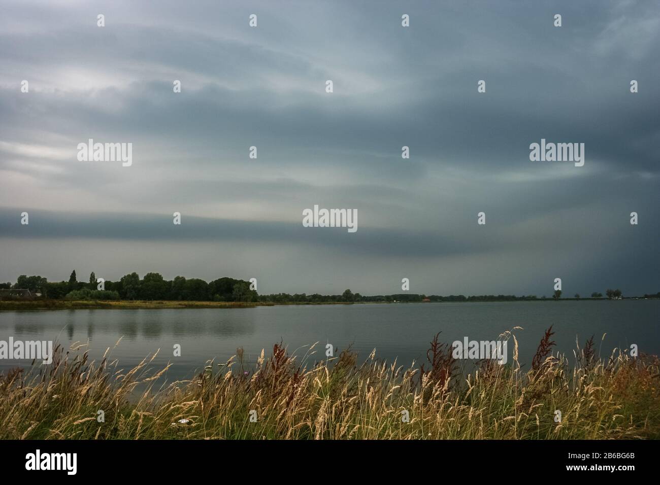 Thunderstorm with smooth laminar shelfcloud over a lake in the Netherlands Stock Photo