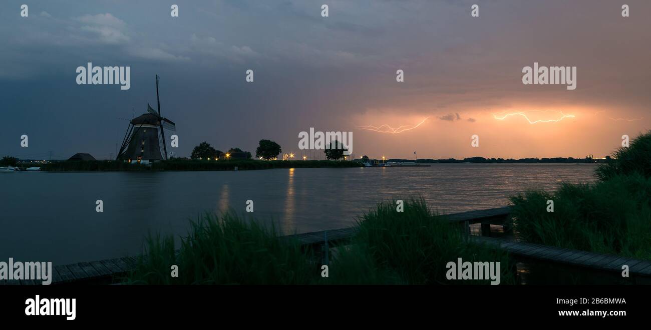 Lightning over a lake with classic dutch windmill, panorama view Stock Photo