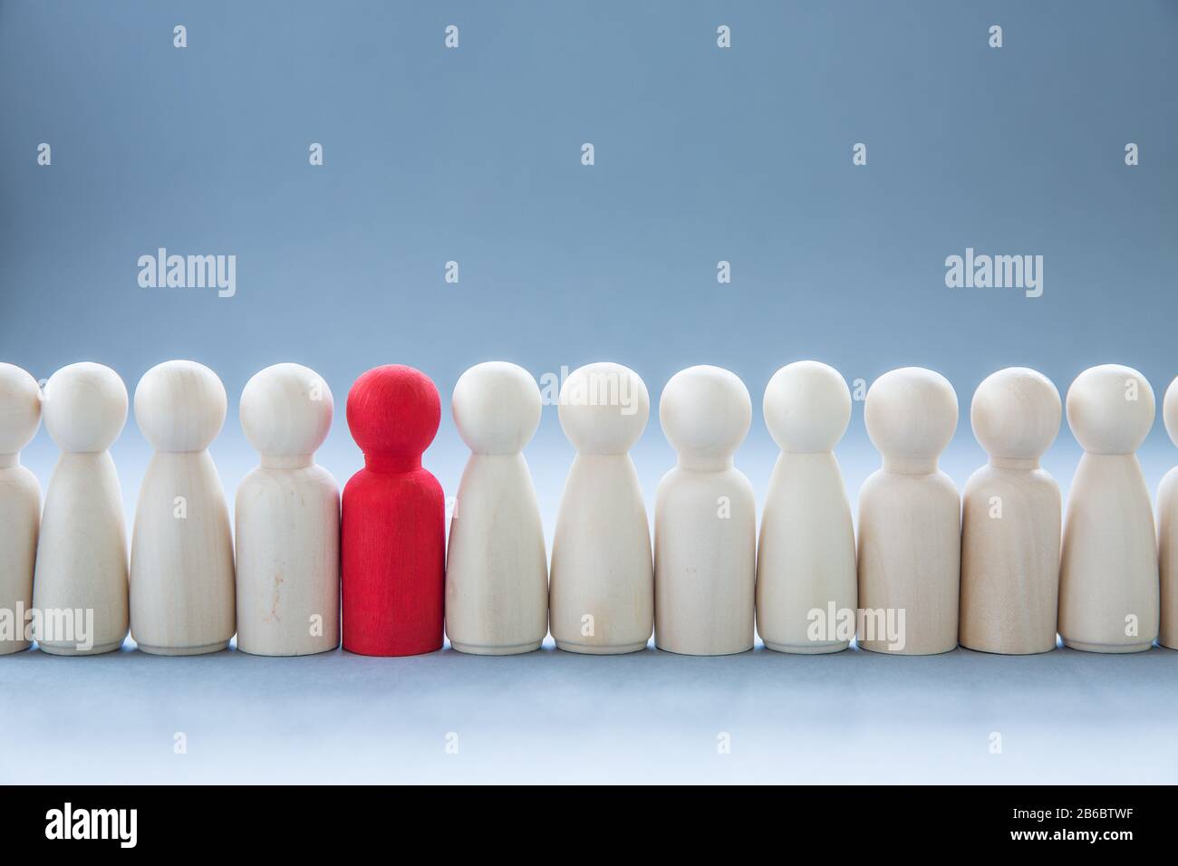 A row of human figures with a single individual standing out from the rest representing individuality and being different such as having a disease lik Stock Photo