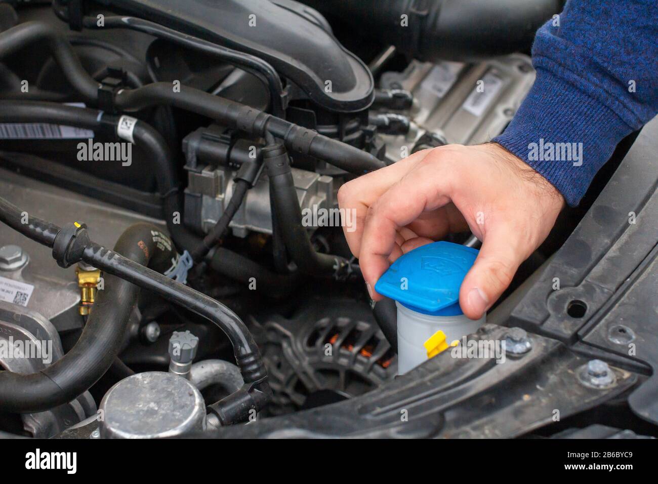 Closeup mans hands checking a level of a glass washer. Car repairing concept. Automobile service. Stock Photo