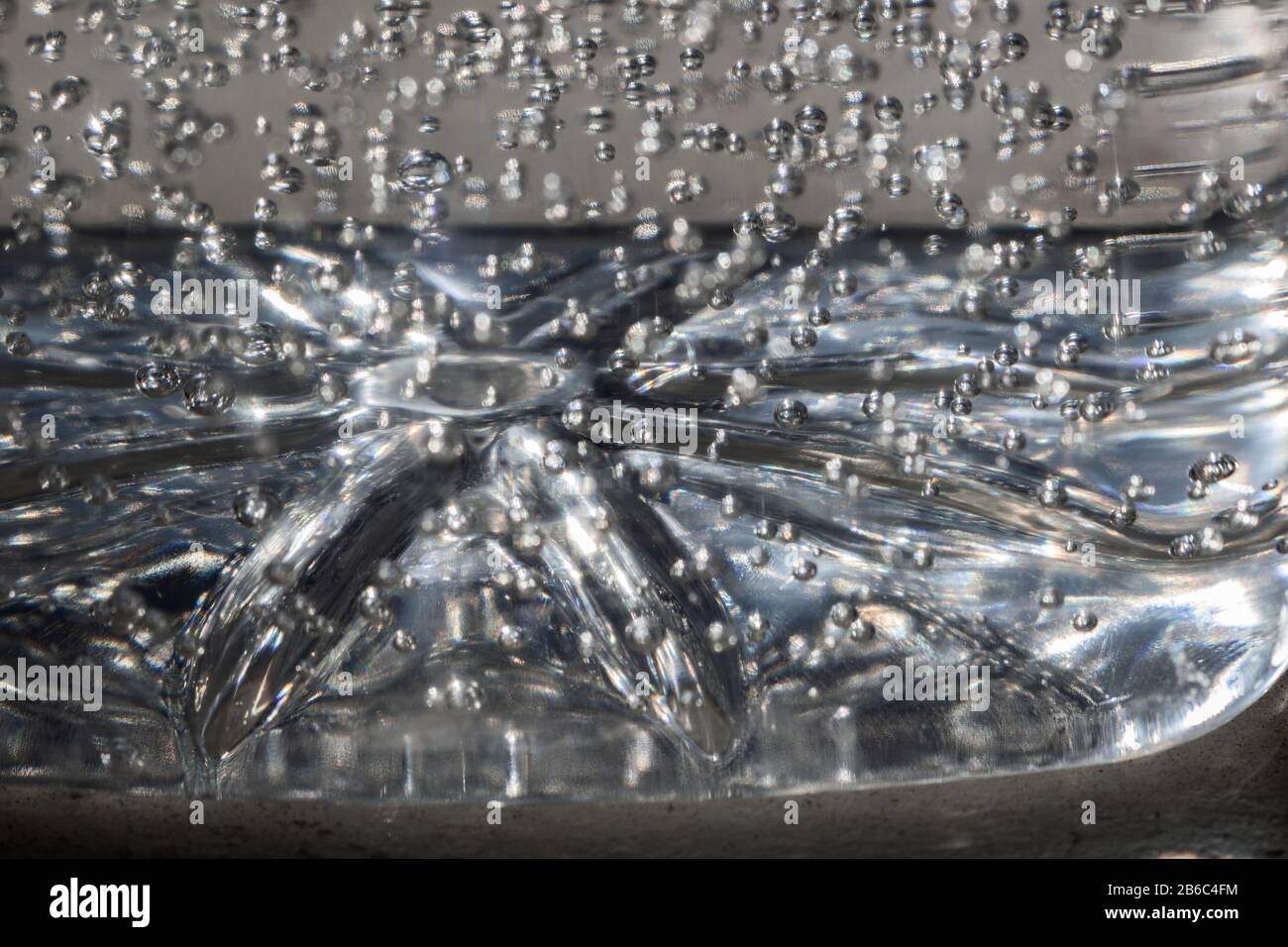 This macro shot of a plastic jug of hand sanitizer shows the bottom of the jug and air bubbles suspended in gel. Stock Photo