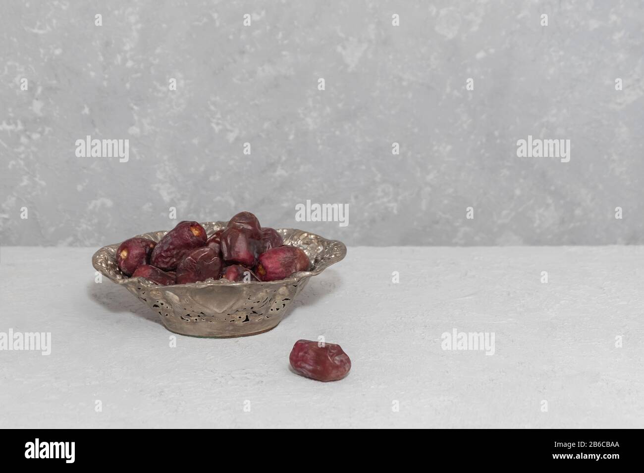 Dry dates in metalic plate on neutral background, copy space. Ramadan fasting concept Stock Photo