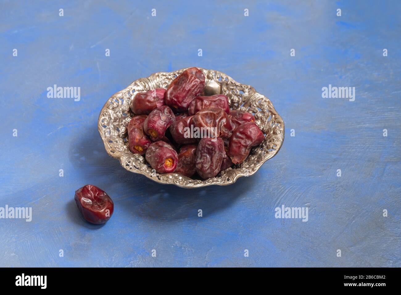 Ramadan fasting composition. Dried dates in a metallic plate on dark blue background Stock Photo