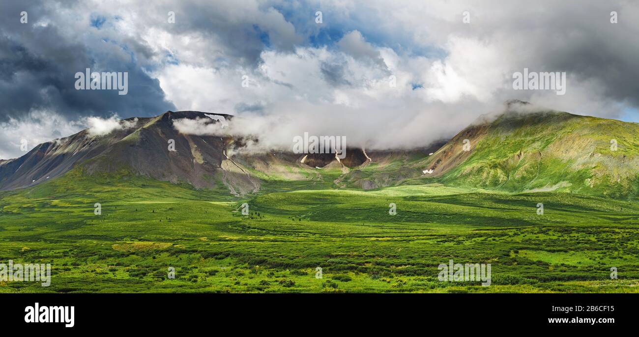 A classic Altai landscape with snow-capped rocky mountains and vast pastures with lush grass Stock Photo