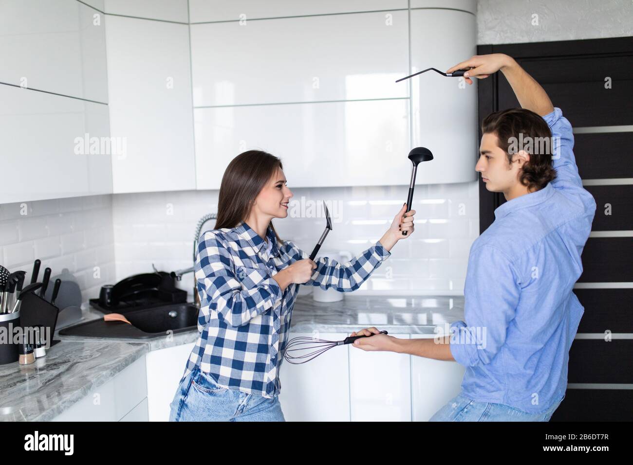 Funny couple pretending fight with utensils tools while cooking at home together, husband and wife having fun feeling playful holding kitchenware stru Stock Photo - Alamy Funny couple pretending fight with utensils tools while cooking at home together, husband and wife having fun feeling playful holding kitchenware stru Stock Photo - Alamy