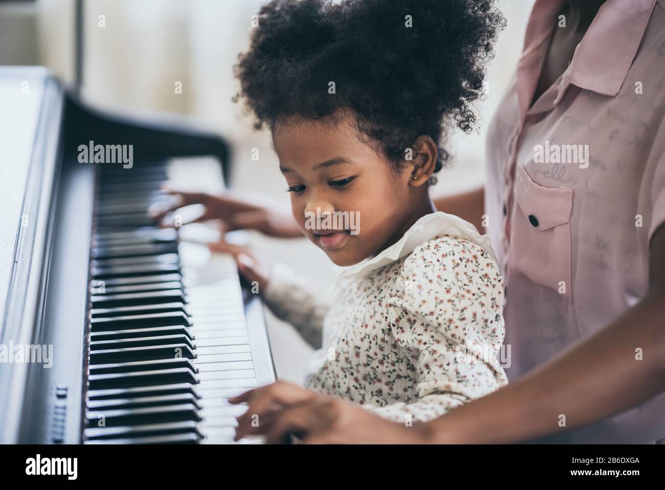 American African young pianist teacher teaching girl kid student