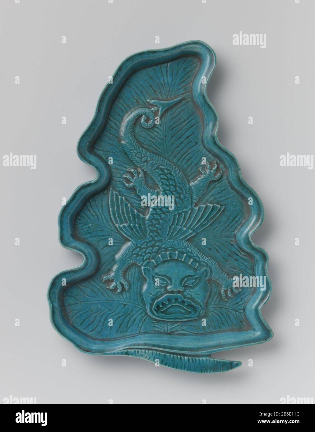 Leaf-shaped dish with dragon Bladvormige onderschotel van dekselkom van porselein, bedekt met een monochroom turquoise, blauw glazuur. De schotel met ingrgrifte nerven en een vliegende, vierklauwige draak in reliëf. Monochromen. Manufacturer : pottenbakker: anoniemPlaats manufacture: China Dating: ca. 1775 - ca. 1799School / stijl: Qing-dynastie (1644-1912) / Qianlong-periode (1736-1795) / Jiaqing-periode (1796-1820) Physical kenmerken: porselein met een monochroom glazuur Material: porselein glazuur Techniek: vormen / bakken / glazuren Dimensions: h 2 cm.  × l 29,4 cm.  × b 19,8 cm. Onderwerp Stock Photo