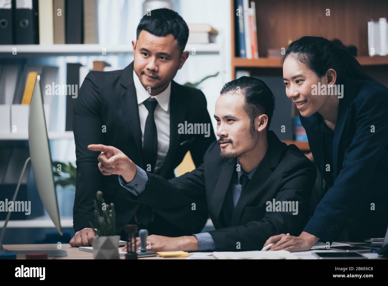 To Discuss Over Coworkers looking at a computer and discussing over new business plan ...