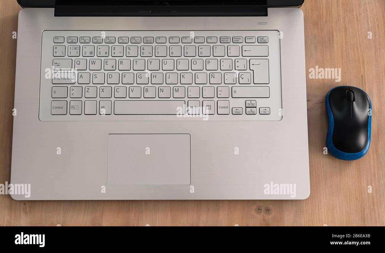 Modern and design grey notebook computer or laptop with keyboard and black and blue laptop in a light wood table Stock Photo