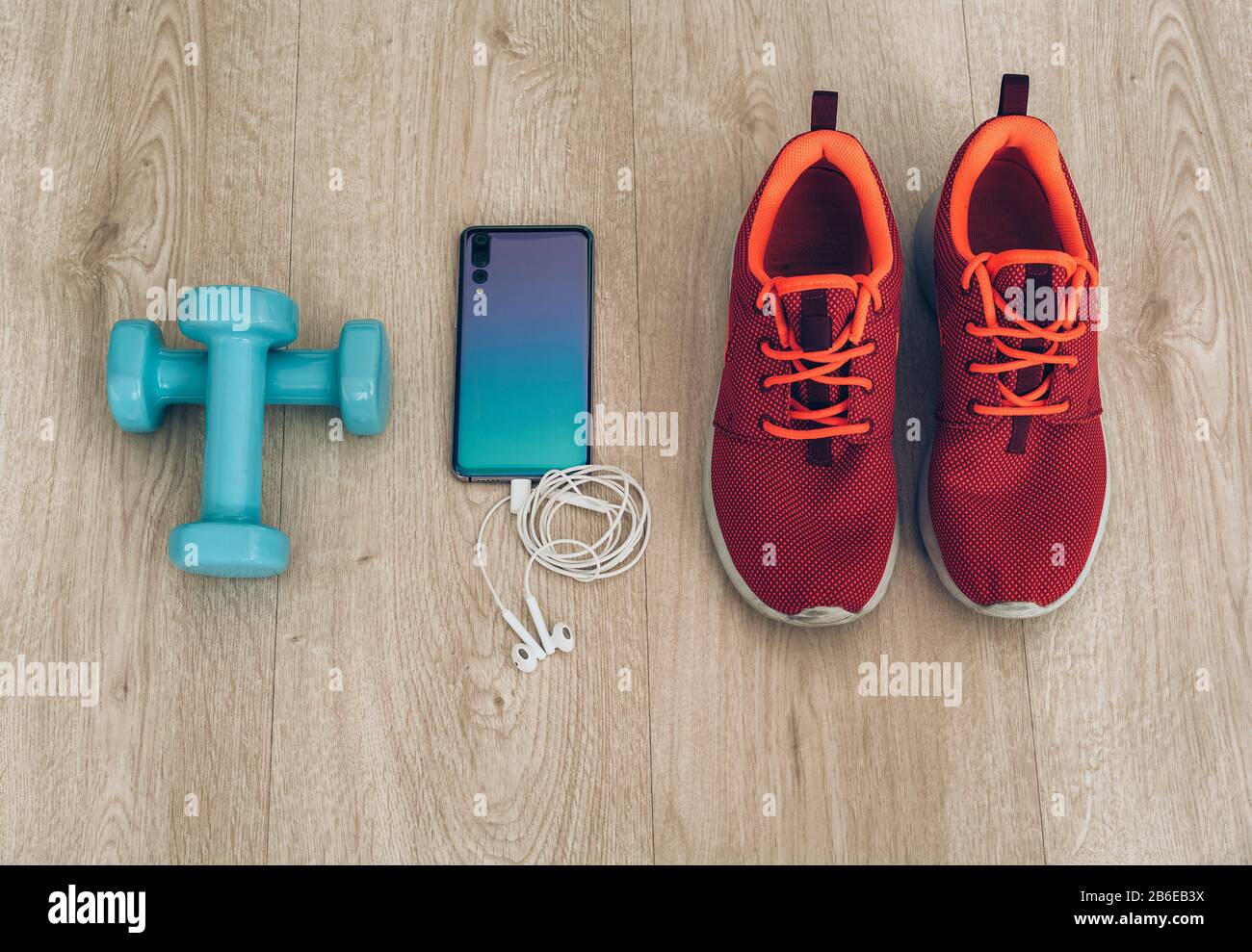 Runner sneakers with cool smartphone, ear phones and smal dumbbells in a  wood background Stock Photo - Alamy