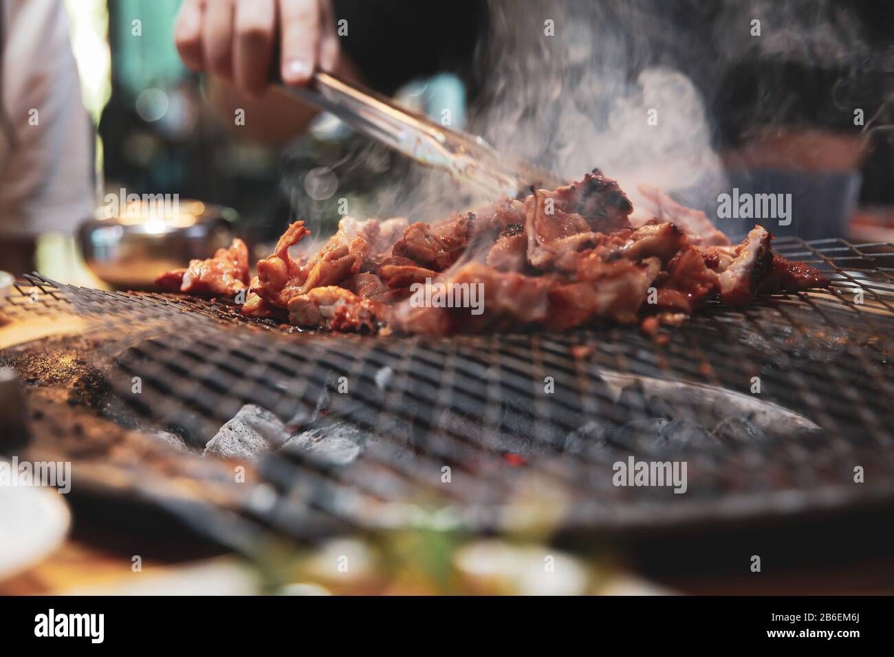 Hand grilling a Korean barbecue ribs meat with smoke Stock Photo