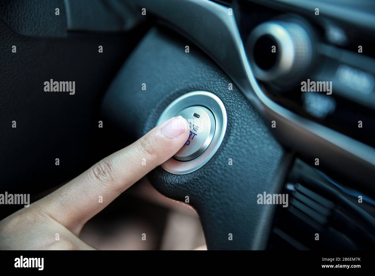 Hand pushing a car engine's Start and stop button Stock Photo