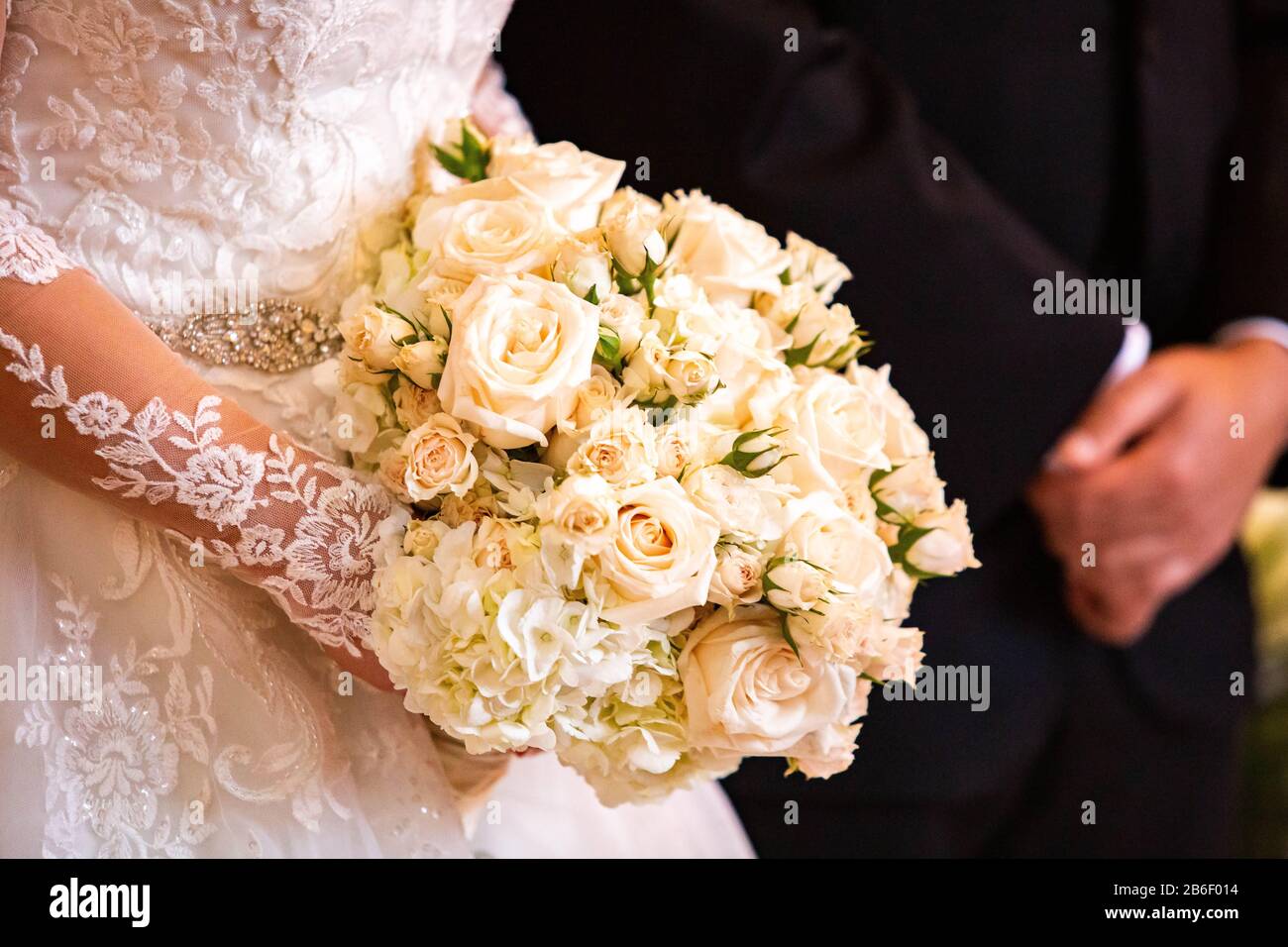 Beautiful bridal wedding bouquet isolated in hands with blurred groom together Stock Photo