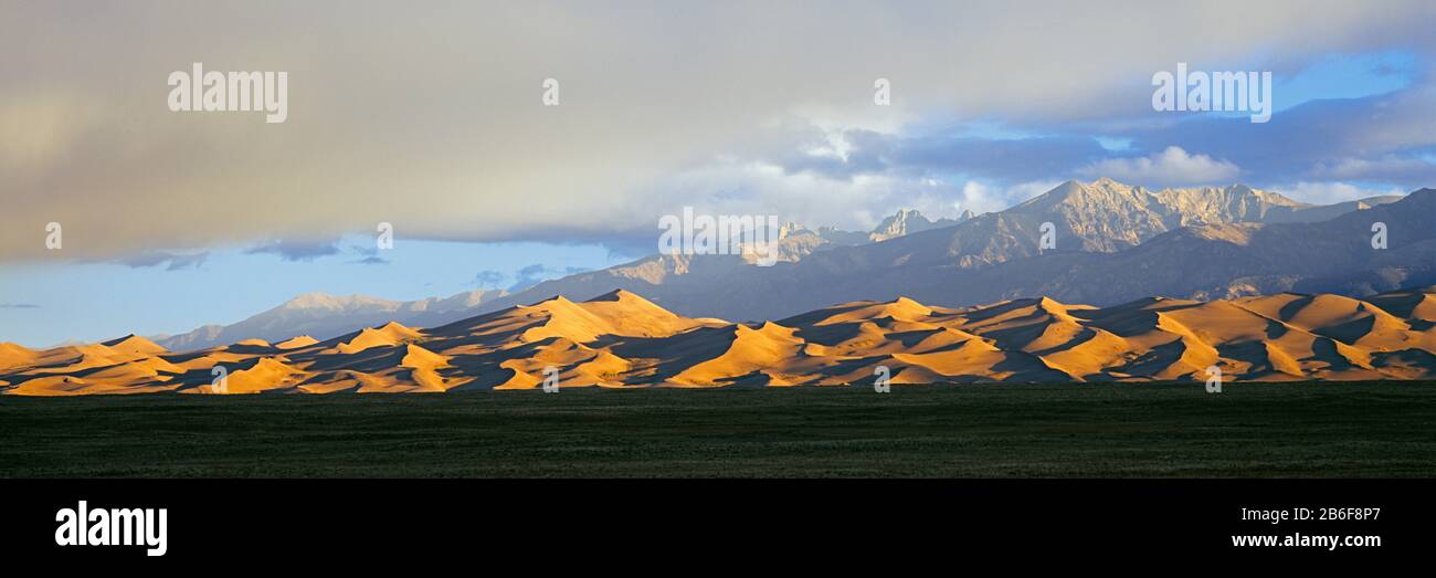 Sand dunes in a desert with a mountain range in the background, Great Sand Dunes National Park, Colorado, USA Stock Photo