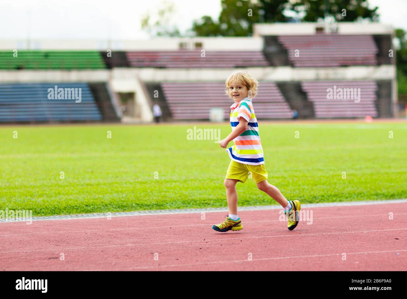 Child running in stadium. Kids run on outdoor track. Healthy sport
