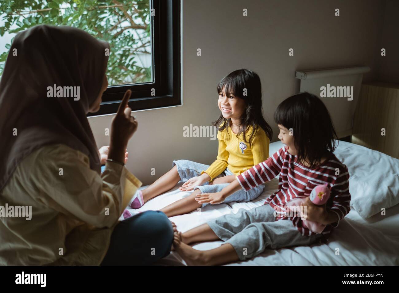 mother storytelling to her daughter on the bed play together Stock Photo