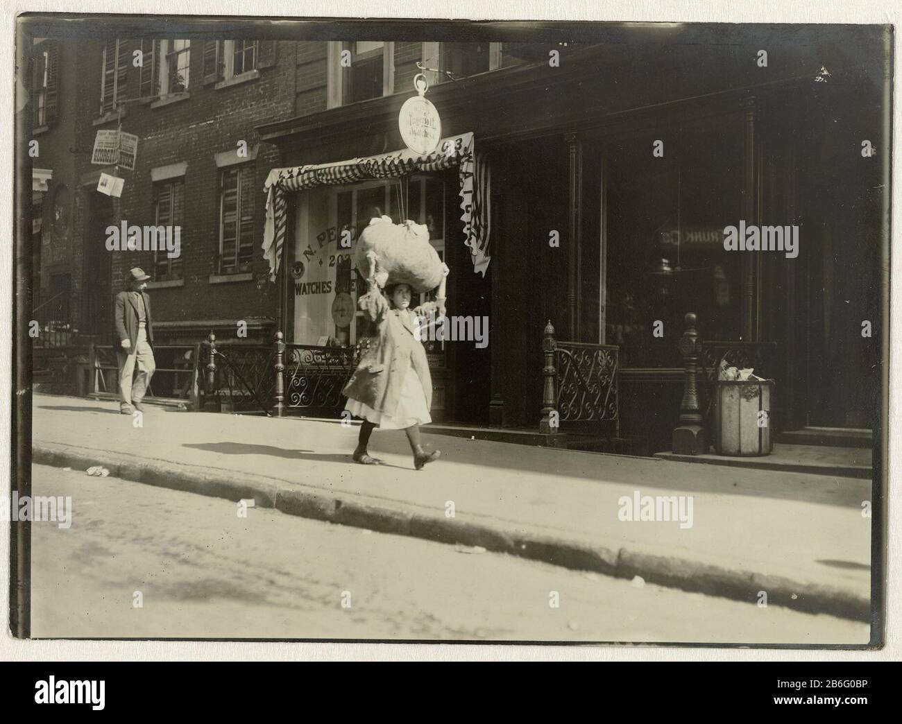 Carrying home-work thro Greenwich Village (titel op object) Child labour (serietitel) Girl on the street in New York with a bundle of fabric on her head . Manufacturer : photographer Lewis Wickes HinePlaats manufacture: New York Date: approx 1909 Physical features: gelatin silver print material: paper Technique: gelatin silver print dimensions: h 126 mm × W 177 mmToelichtingDe photographer Hine worked for the National Child Labor Committee from 1906 to 1917, and photographed children worked in coal mines and fabrieken. Date: 1906 - 1917 Stock Photo