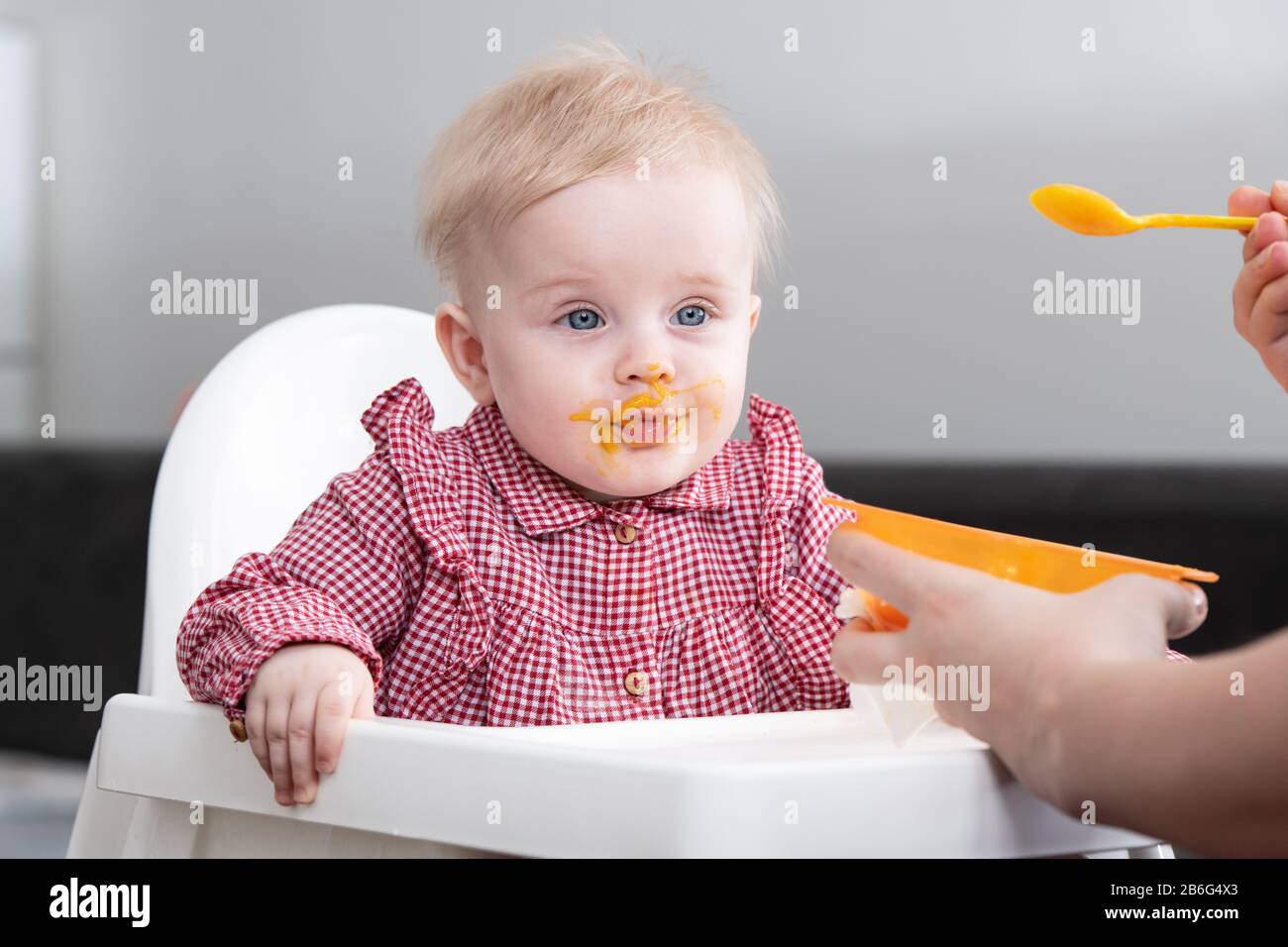 Mother Feeding Her Baby Daughter With Spoon - Mother Giving Healthy Food To Her Adorable Child At Home Stock Photo