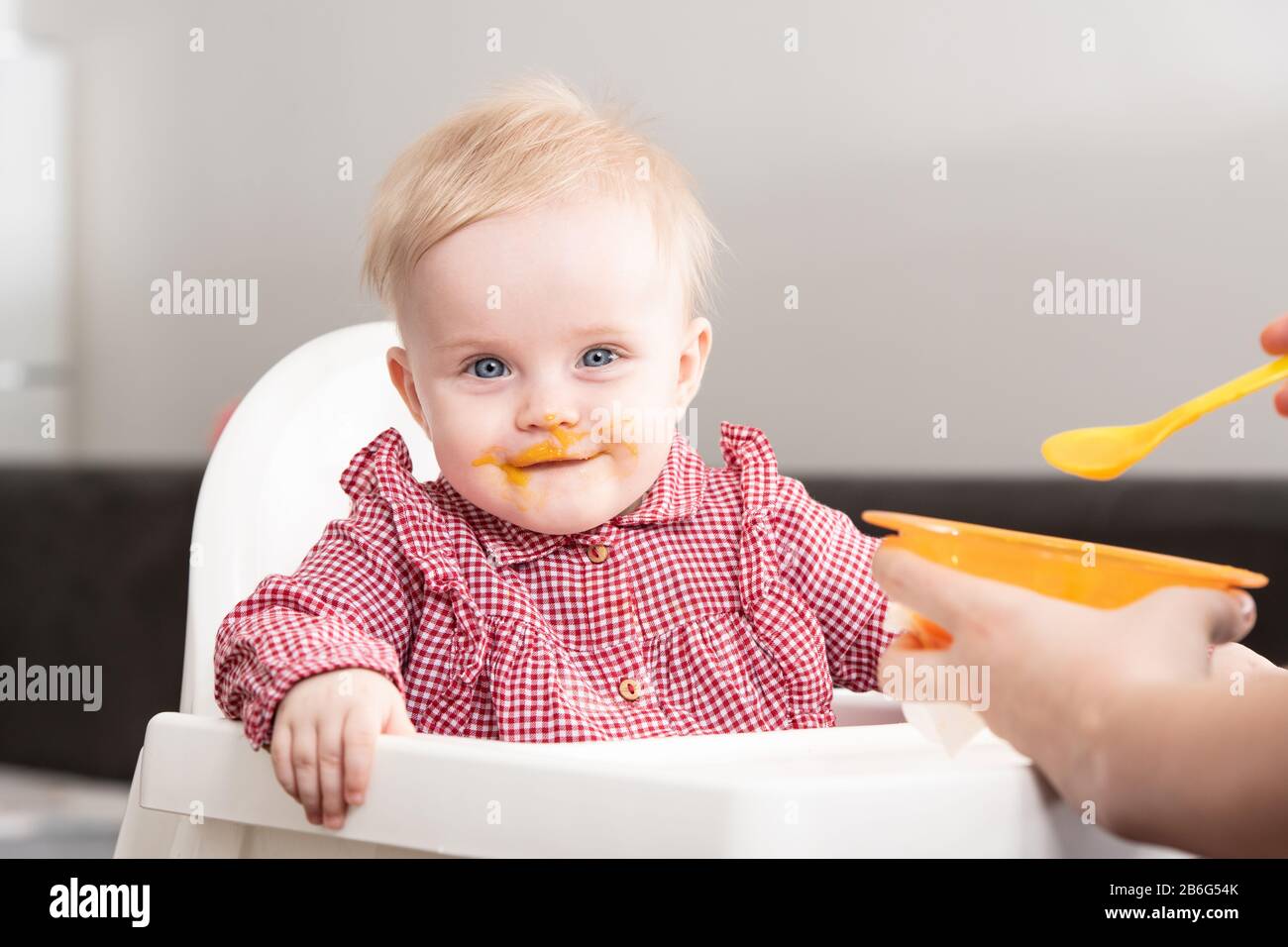 Mother Feeding Her Baby Daughter With Spoon - Mother Giving Healthy Food To Her Adorable Child At Home Stock Photo