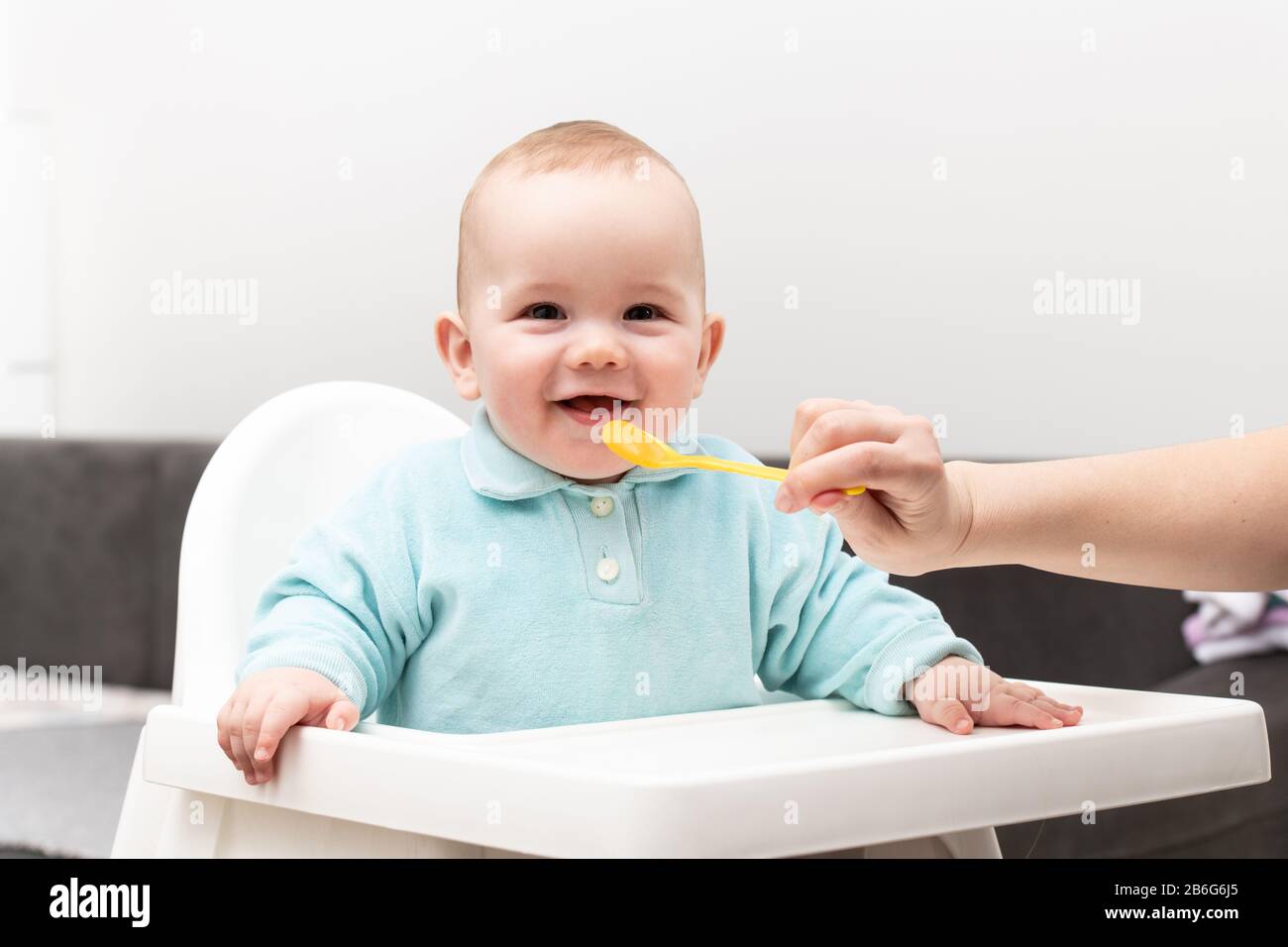 Mother Feeding Her Baby Son With Spoon - Mother Giving Healthy Food To Her Adorable Child At Home Stock Photo