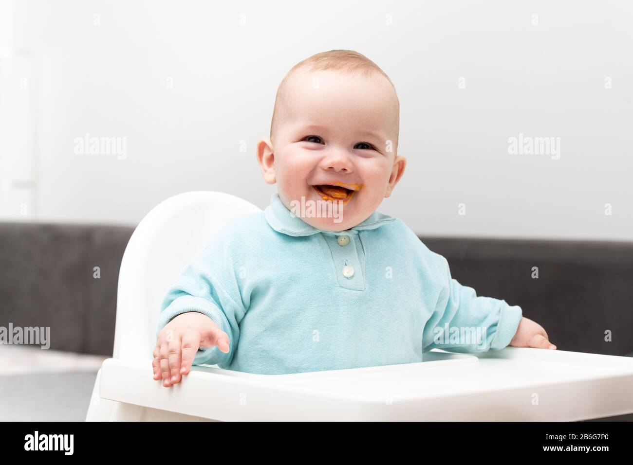 Mother Feeding Her Baby Son With Spoon - Mother Giving Healthy Food To Her Adorable Child At Home Stock Photo