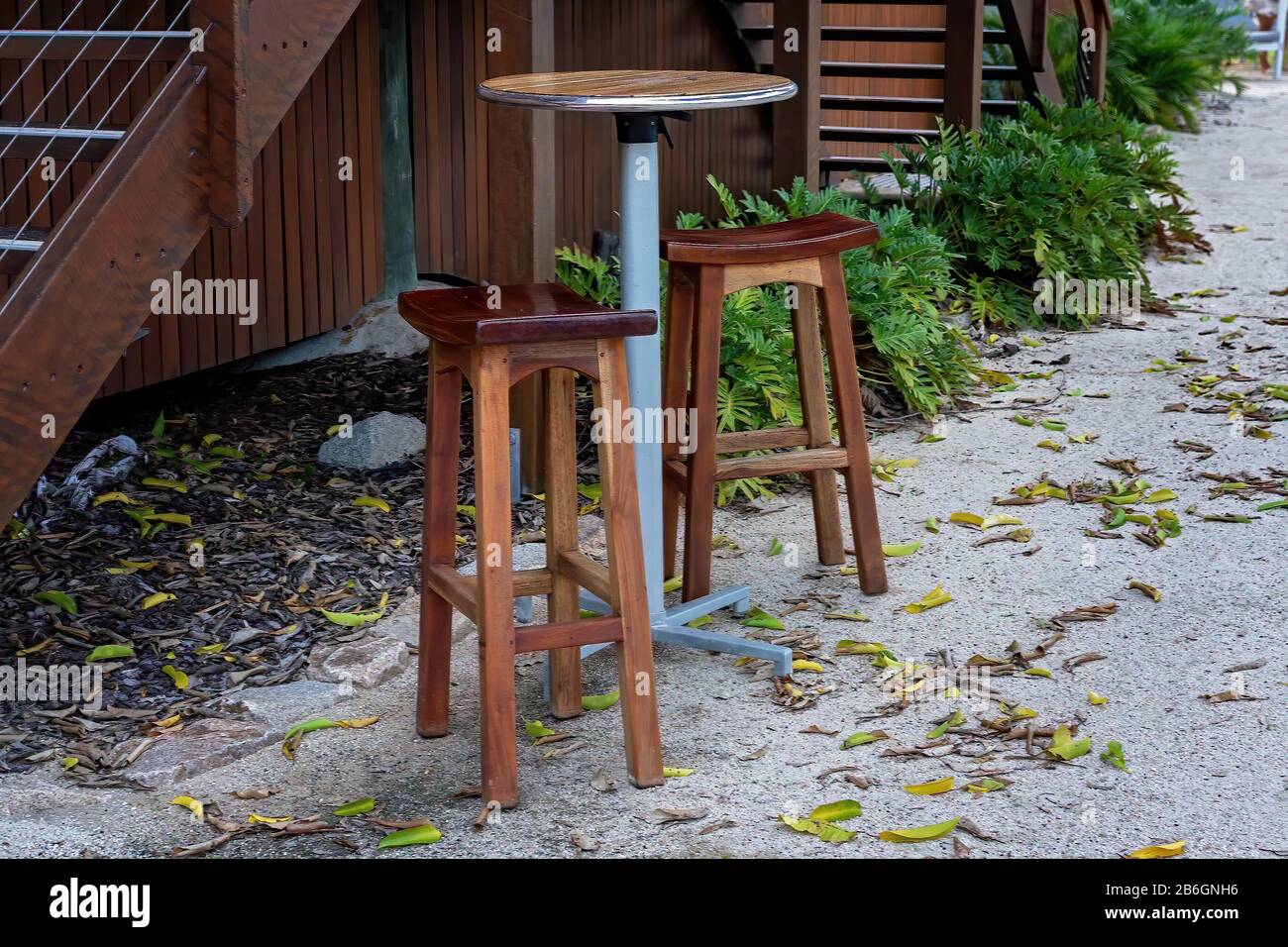 Timber bar stools and table sitting on the sand beside a set of stairs