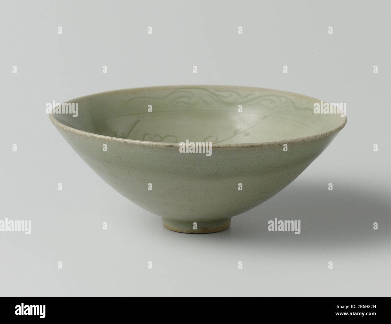 Conical bowl with incised prunus and cloud motif Conische kom van porselein, bedekt met een groen glazuur. Op de binnenwand een ingegrifte punus en wolkmotieven. Op de binnenrand een decoratieve band met twee gestileerde bladranken. Celadon. Manufacturer : pottenbakker: anoniemPlaats manufacture: China Dating: ca. 1200 - ca. 1299School / stijl: Song-dynastie (960-1279) / Yuan-dynastie (1279-1368) Physical kenmerken: steengoed met een celadon glazuur Material: porselein glazuur Techniek: draaiend bewerken / graveren (inkerven) / bakken / glazuren Dimensions: h 5 cm. rand: d 12,6 cm. voet: d 2,9 Stock Photo