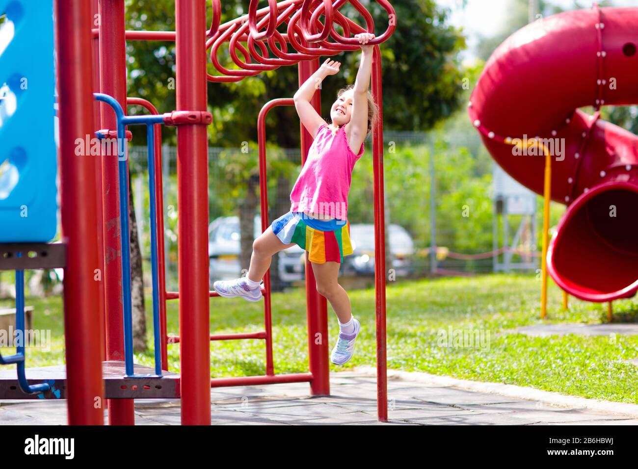 Child on monkey bars. Kid at school playground. Little girl hanging on