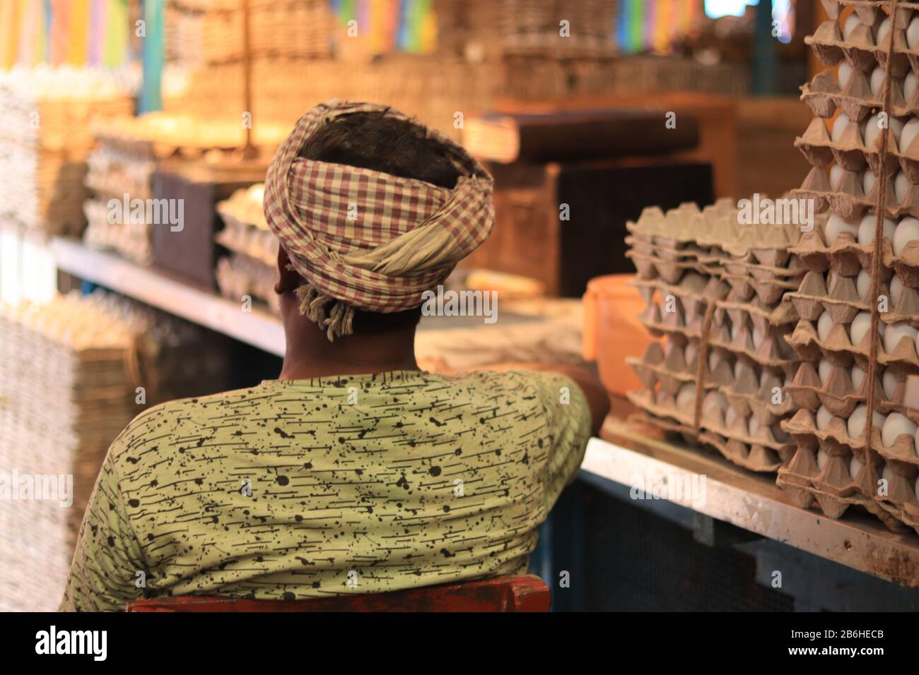 A man sits next to crates of eggs inside Hogg Market Stock Photo