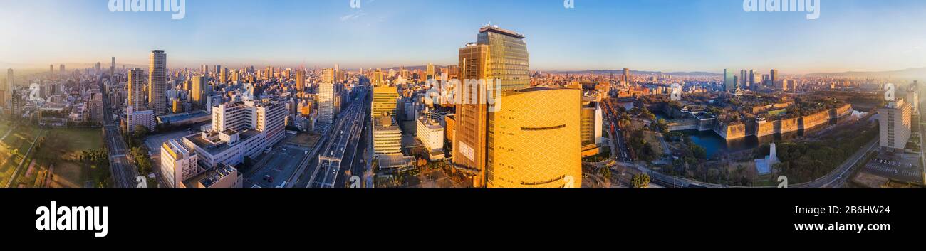 Ultra wide aerial panorama of Osaka city at sunrise with endless urban skyline of skyscrapers and old parks. Stock Photo