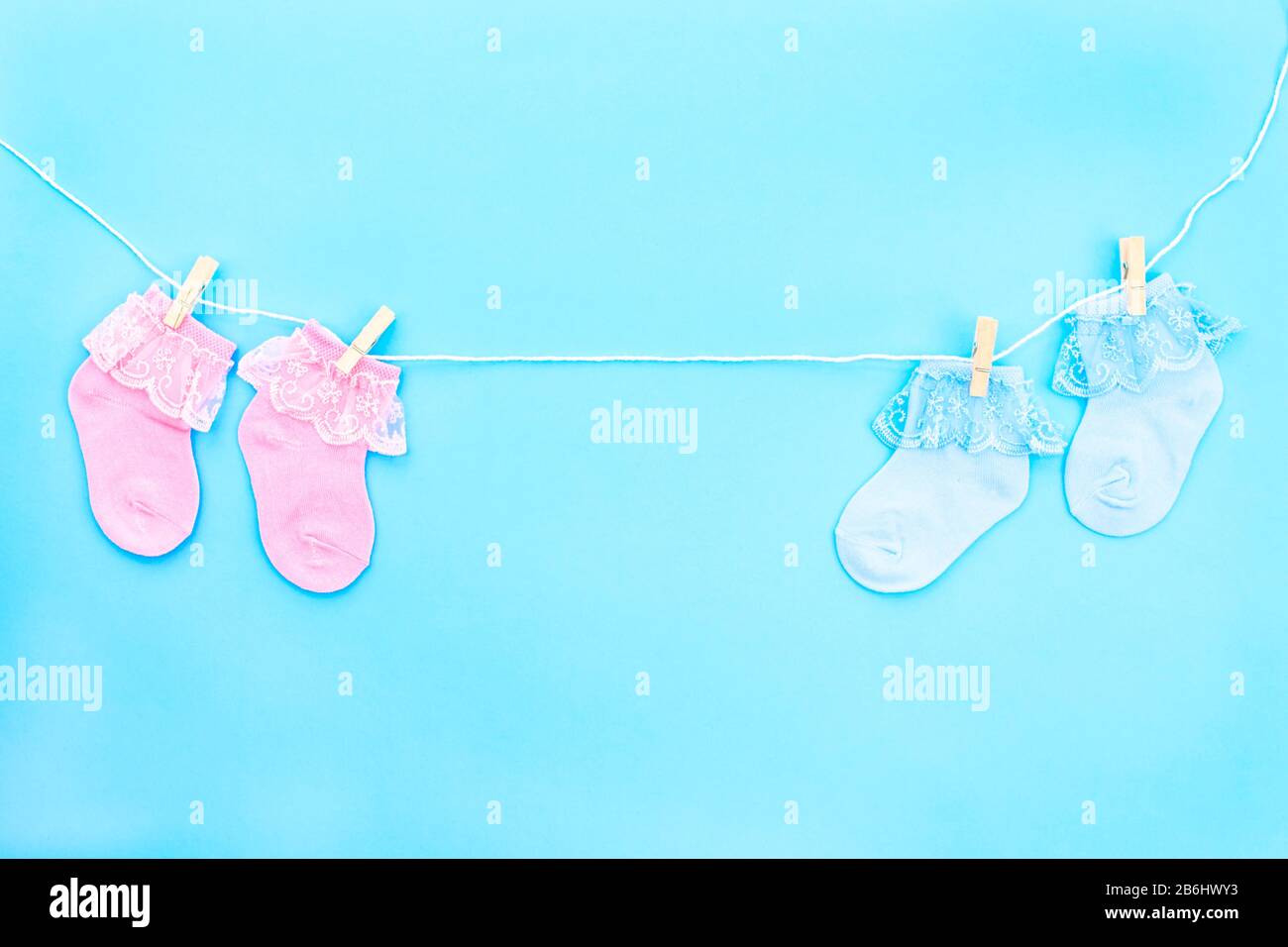 Colorful cute baby socks hanging on the clothesline on blue background