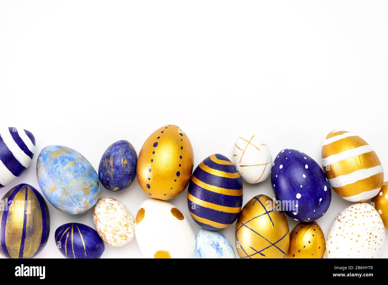 Happy Easter. Frame for text made of easter eggs trendy colored classic blue, white and golden on white. Minimal style, top view, flatlay, copy space. Stock Photo