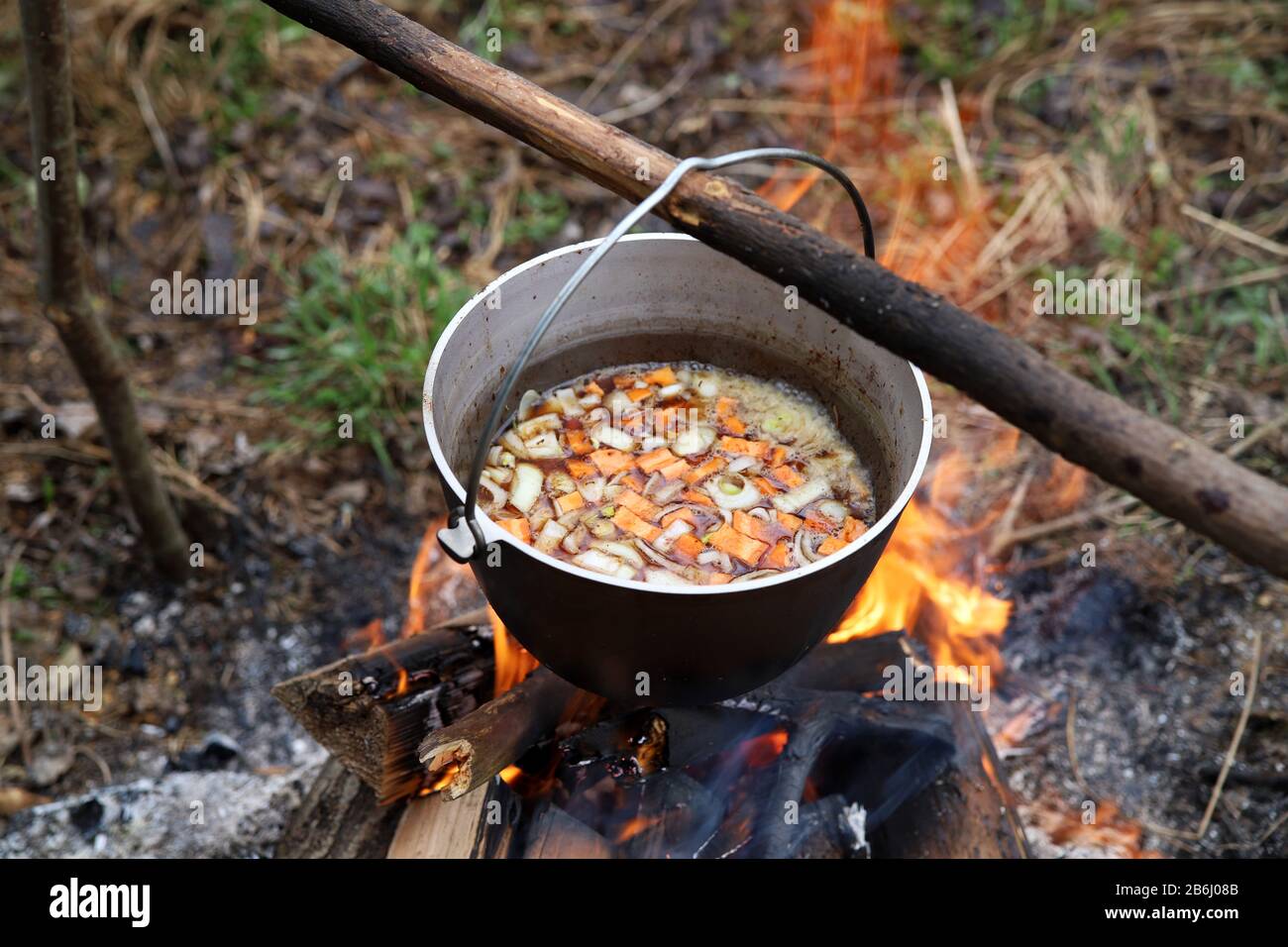 Cooking vegetable soup in cauldron on campfire in the camp. Food in