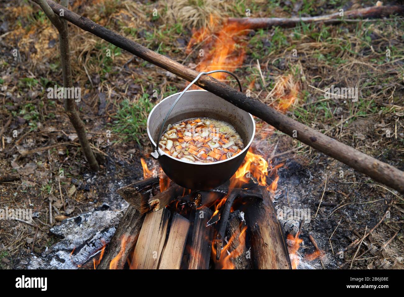 Cooking vegetable soup in cauldron on campfire in the camp. Food in