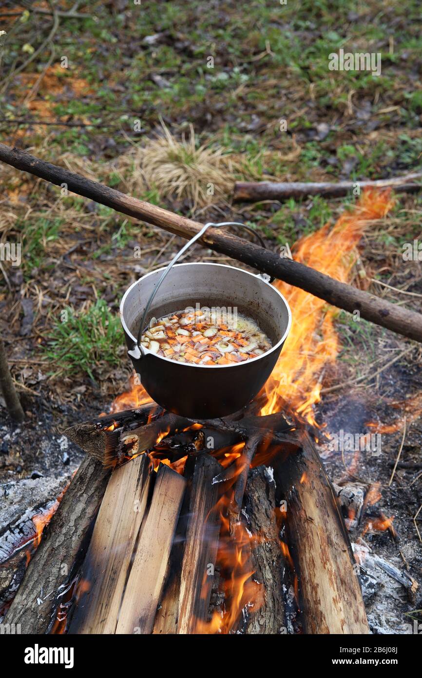 Cooking vegetable soup in cauldron on campfire in the camp. Food in