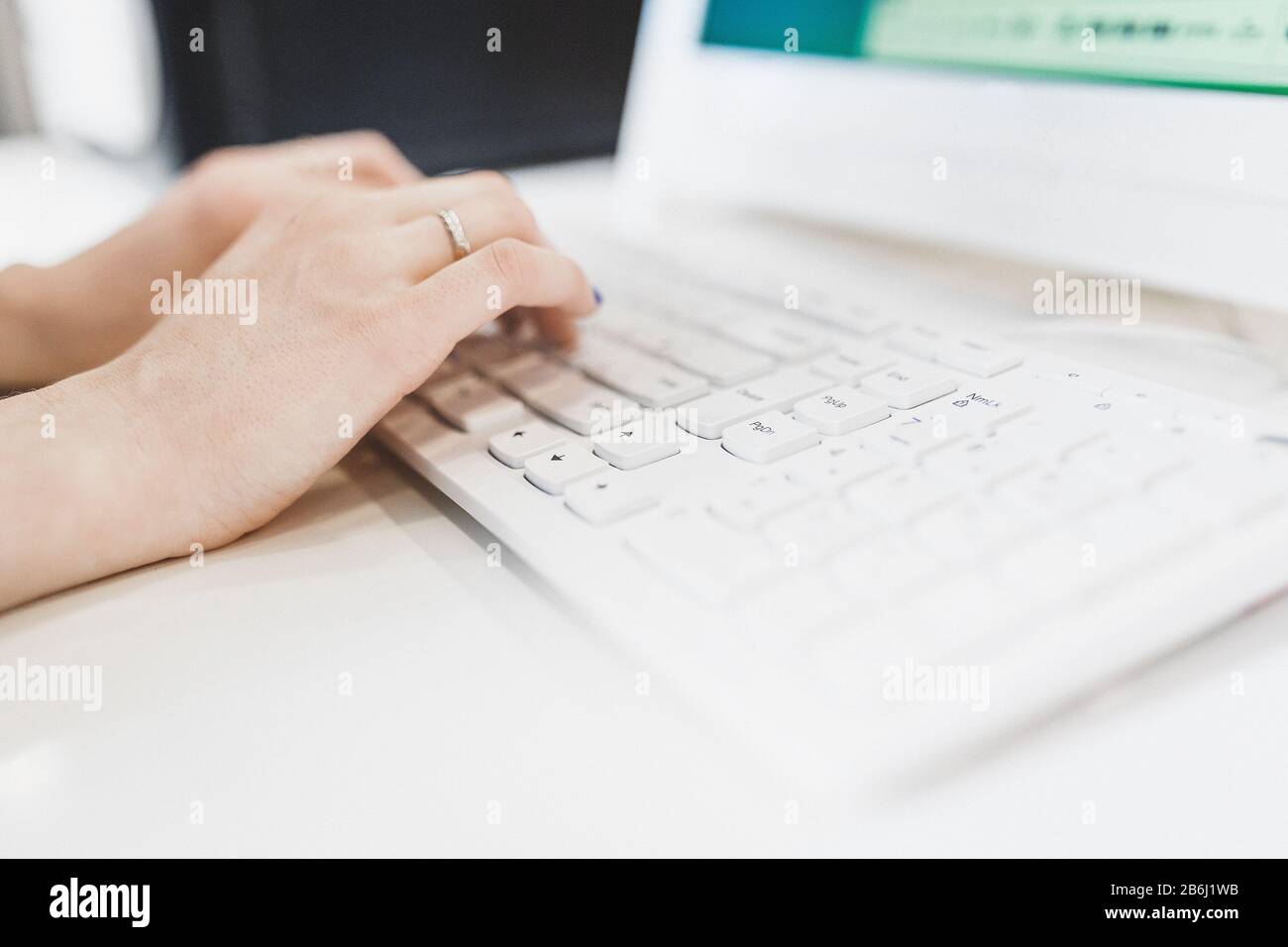 side view of the woman hands typing on a white keyboard closeup Stock Photo