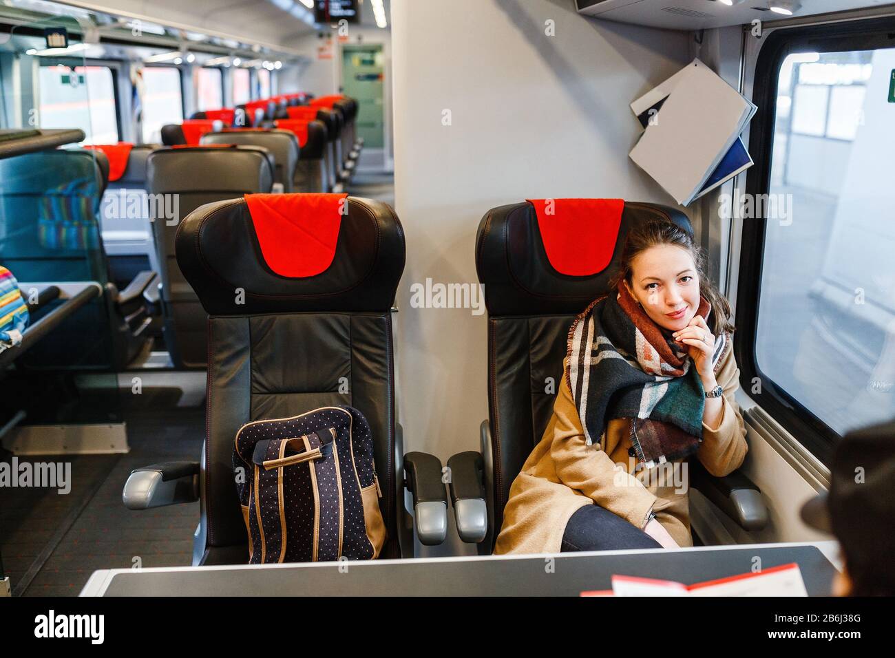Happy Woman travels by train in a sitting car and looks out the window
