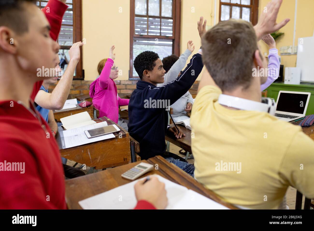 Side view of students raising their hands in class Stock Photo