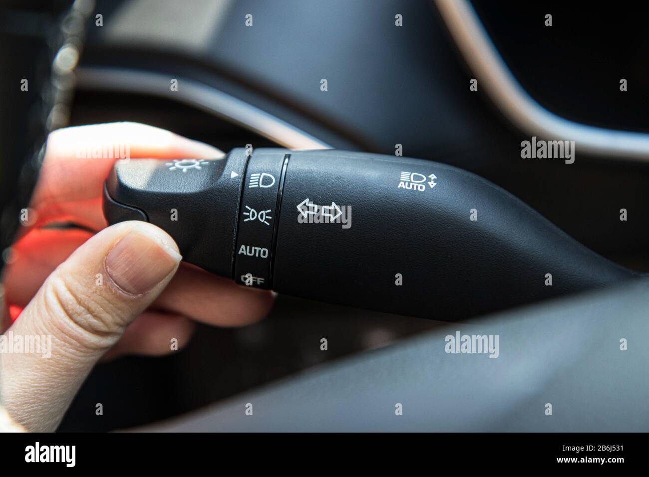 Hand holding a car wiper handle and lighting switch control in a modern