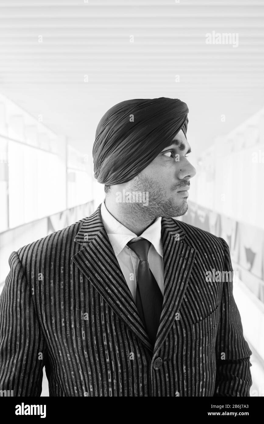 Young handsome Indian Sikh businessman wearing turban in the city Stock Photo