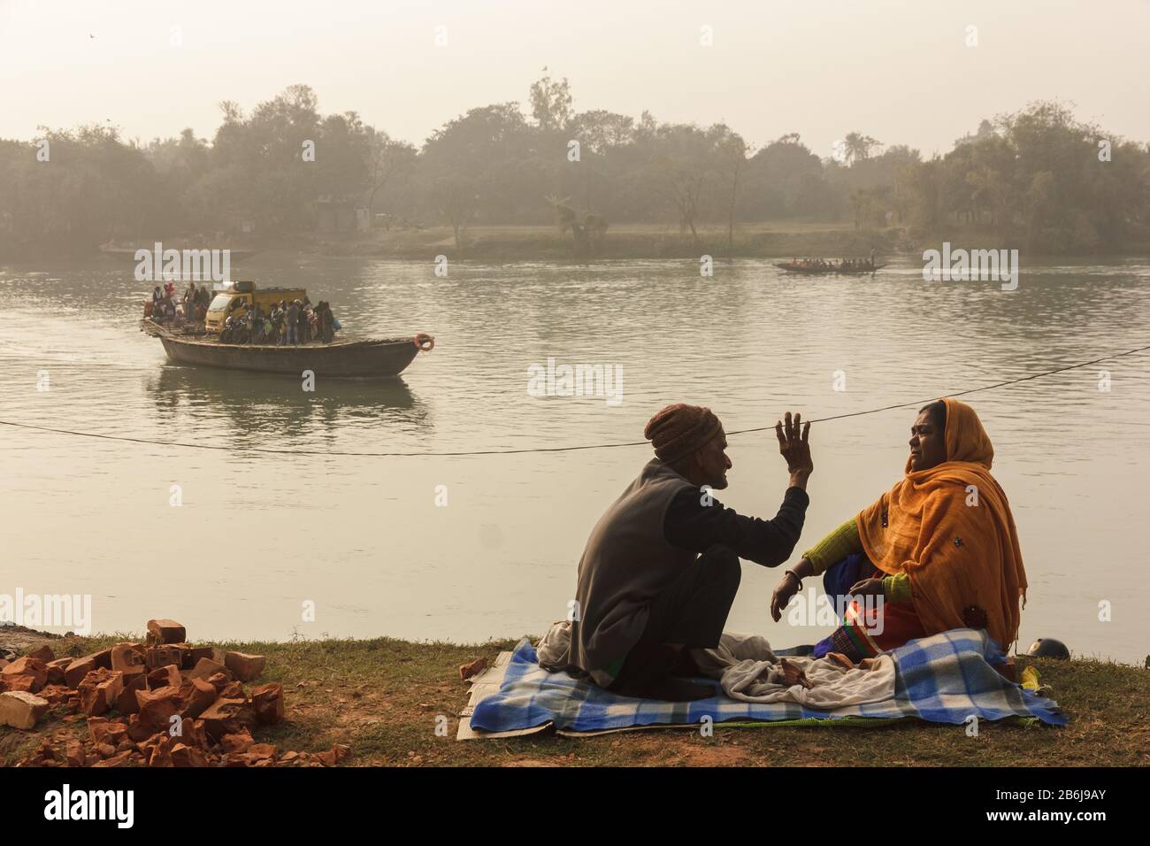 Murshidabad, West Bengal/India - January 14 2018: A man and a woman have an animated conversation as a wooden boat ferries passengers. Stock Photo