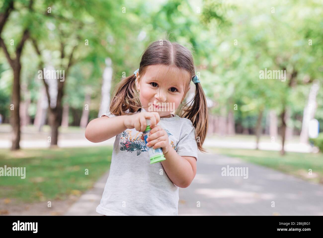 Cute little girl is blowing a soap bubbles in park Stock Photo - Alamy