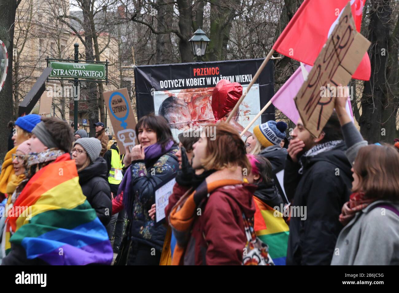 Cracow. Krakow. Poland. Manifa. Women demonstrate for equal rights on International Women's Day. Graphic anti-choice banners in the background. Stock Photo