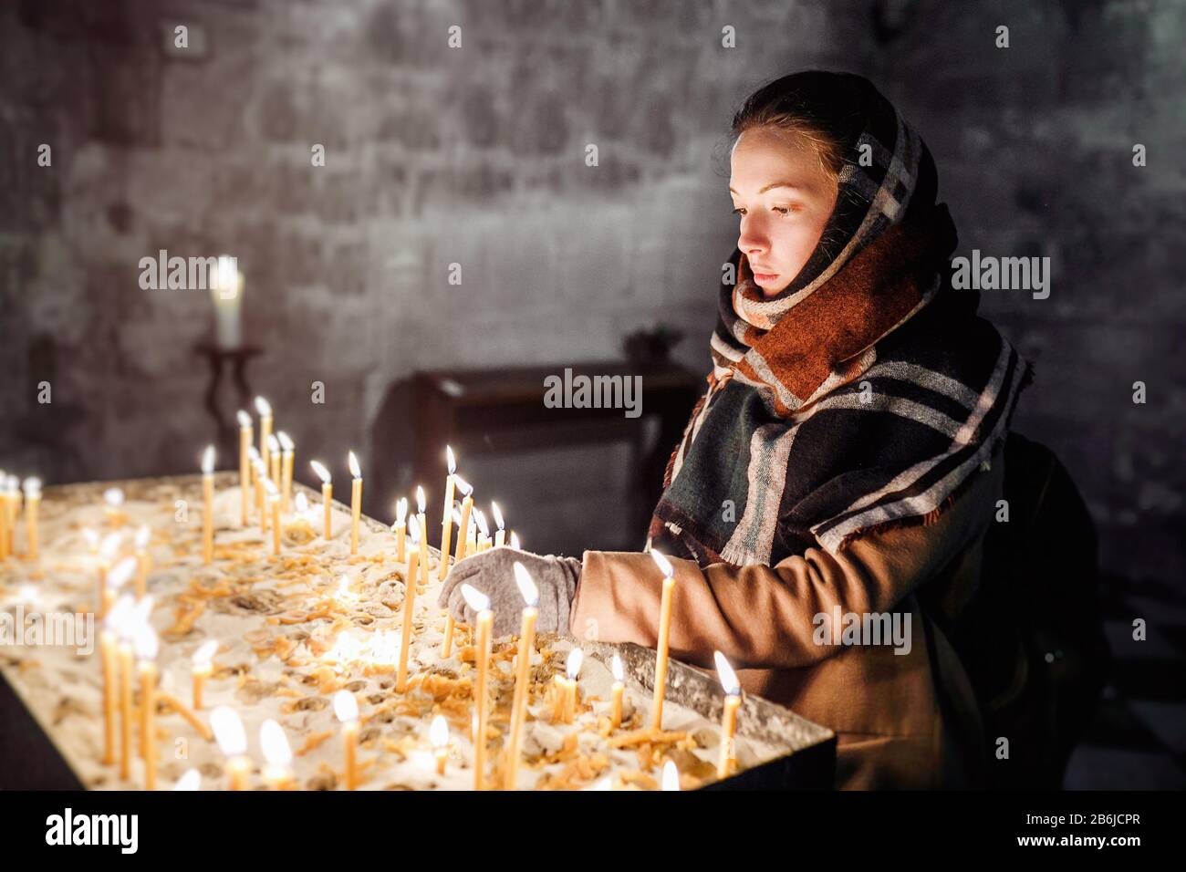 Young woman lighting candles in a church during praying Stock Photo Alamy