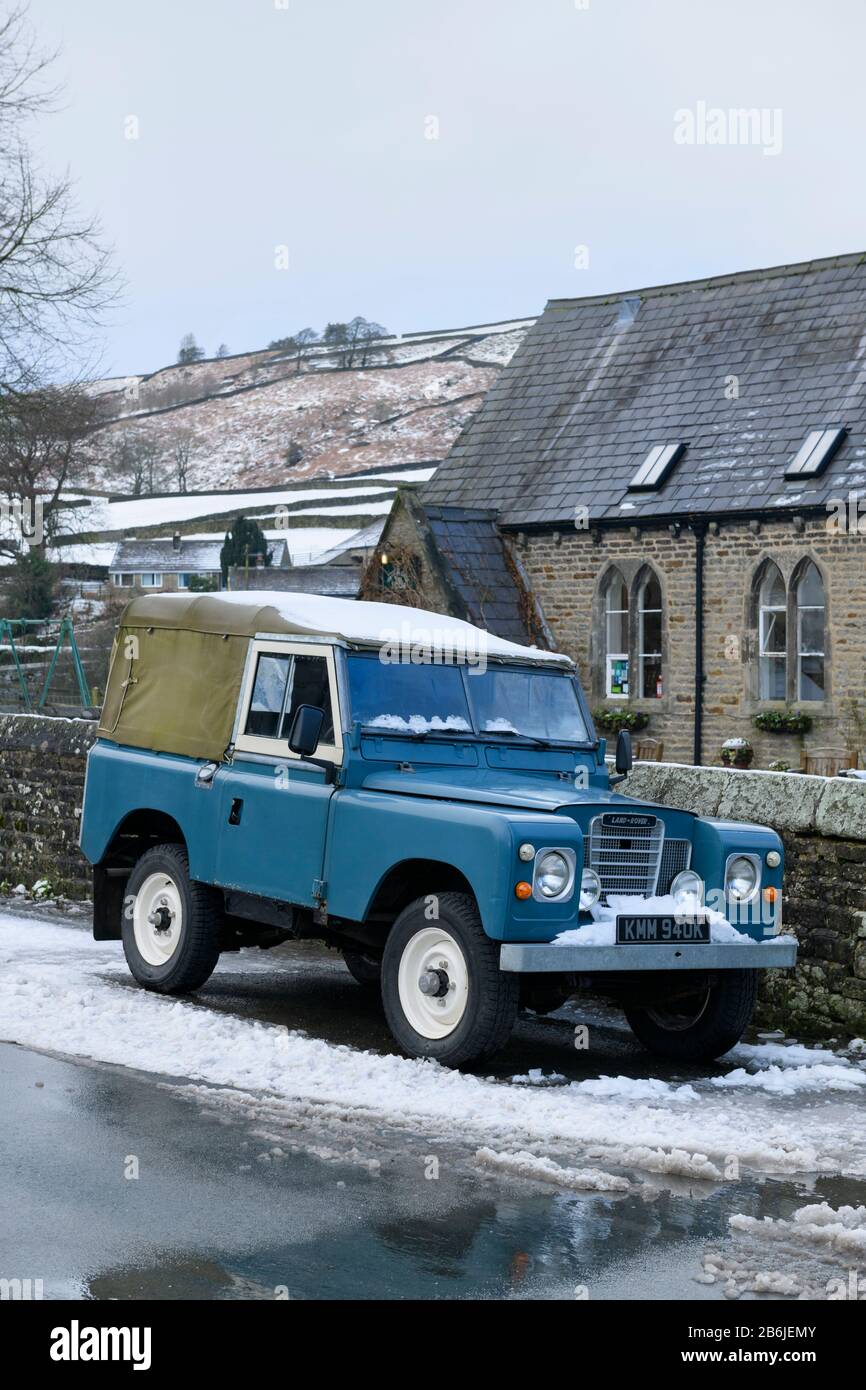Iconic classic rugged blue Series 3 Land Rover 4x4 off-road vehicle, parked in winter snow in scenic village - Hebden, Yorkshire Dales  England, UK. Stock Photo
