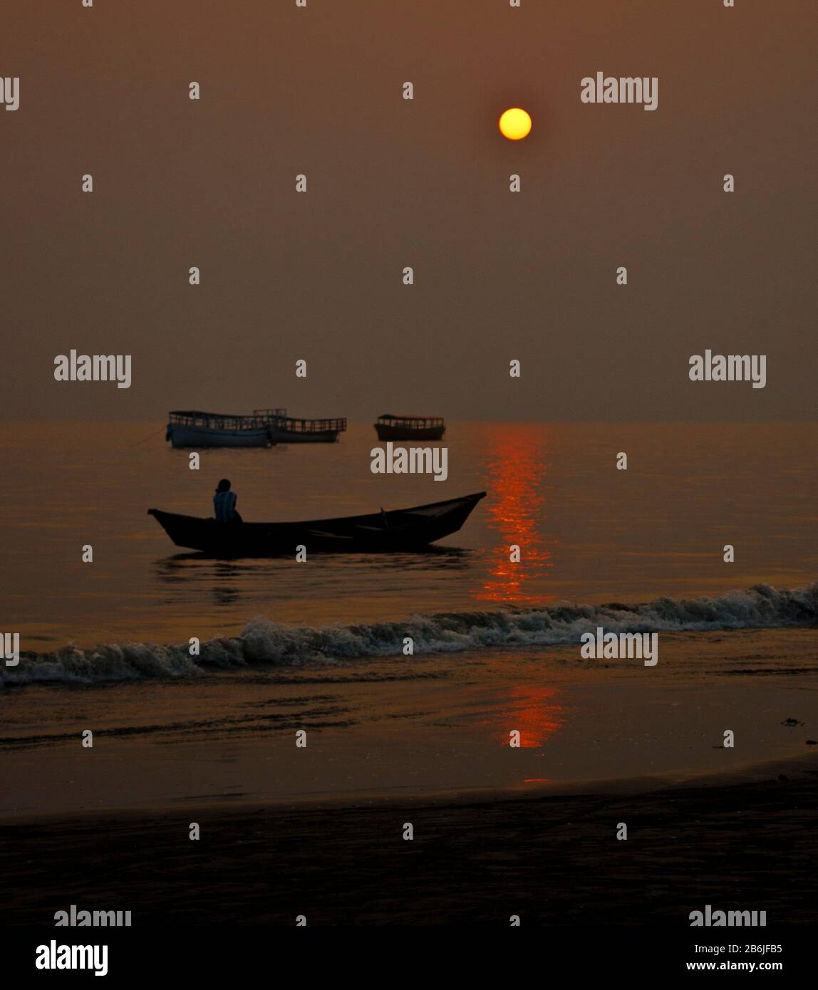 A day is ending as sun is setting on Bay of Bengal and  a tiny fishing  boat is passing through the shadow. Some other fishing boat is going to port. Stock Photo