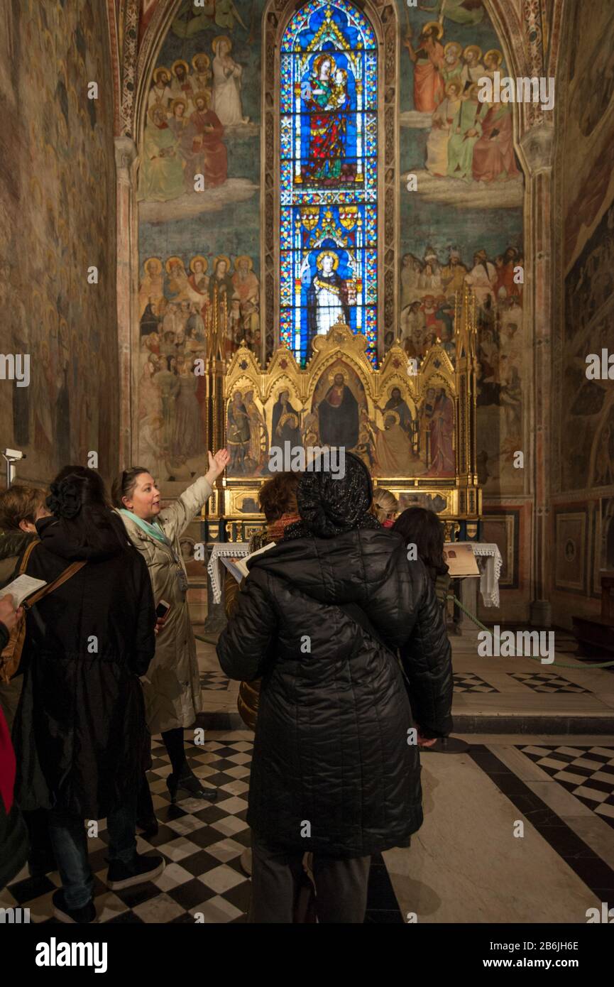 Florence, Italy - 2020, March 1: Tour guide shows the masterpieces kept in a Chapel of the Basilica of Santa Maria Novella. Stock Photo