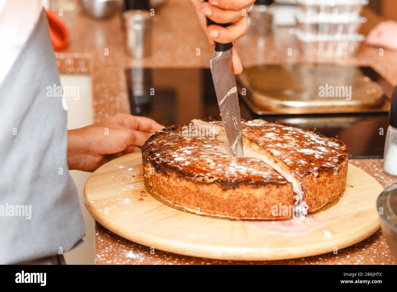 chefs hands with knife cutting baked Basque pie Stock Photo Alamy