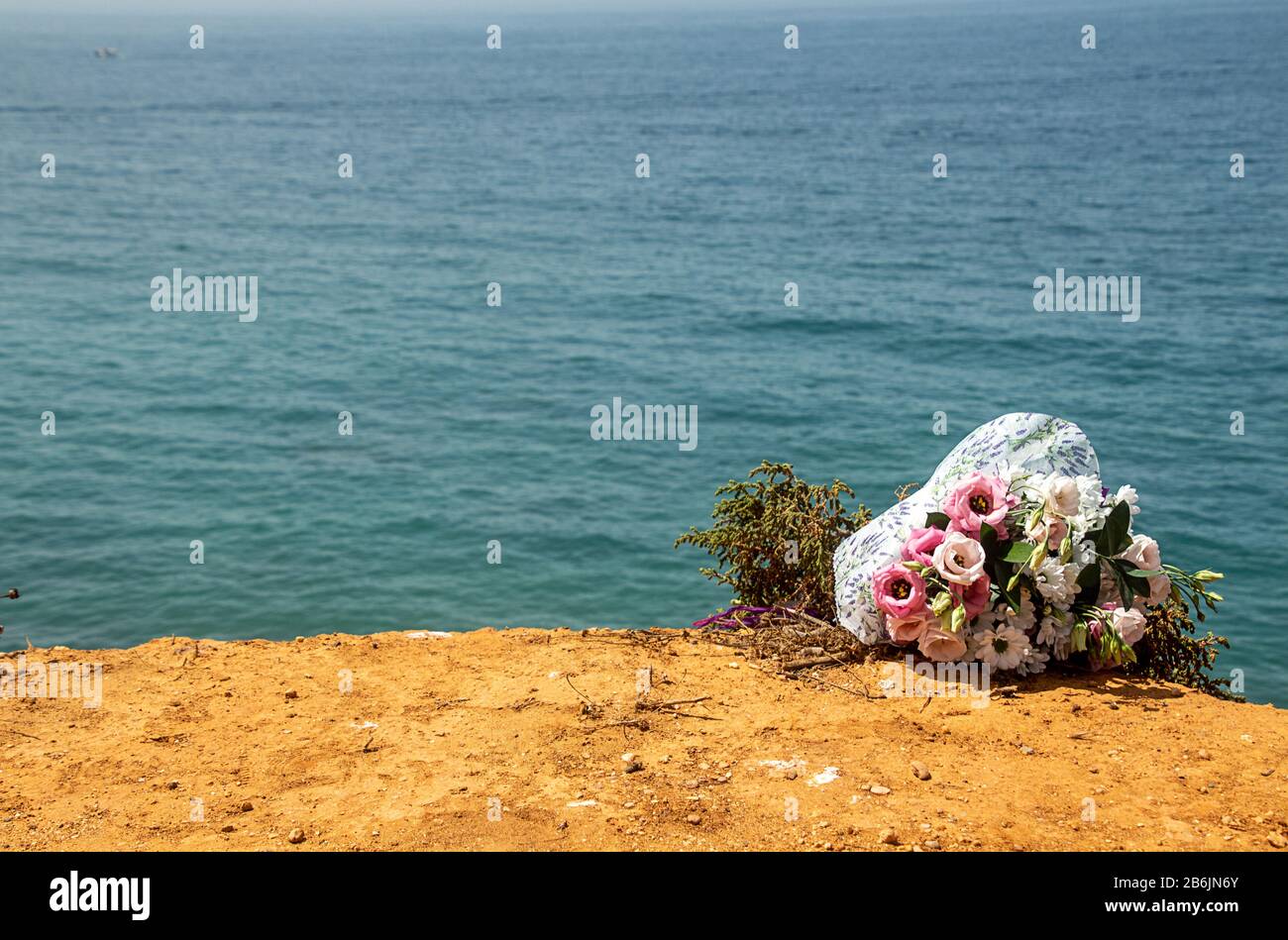 Funeral flowers at the beach. Flower bouquet on doom place, memory, Atlantic ocean, spanish seashoore. copy space,  Funeral symbol and Condolence card Stock Photo
